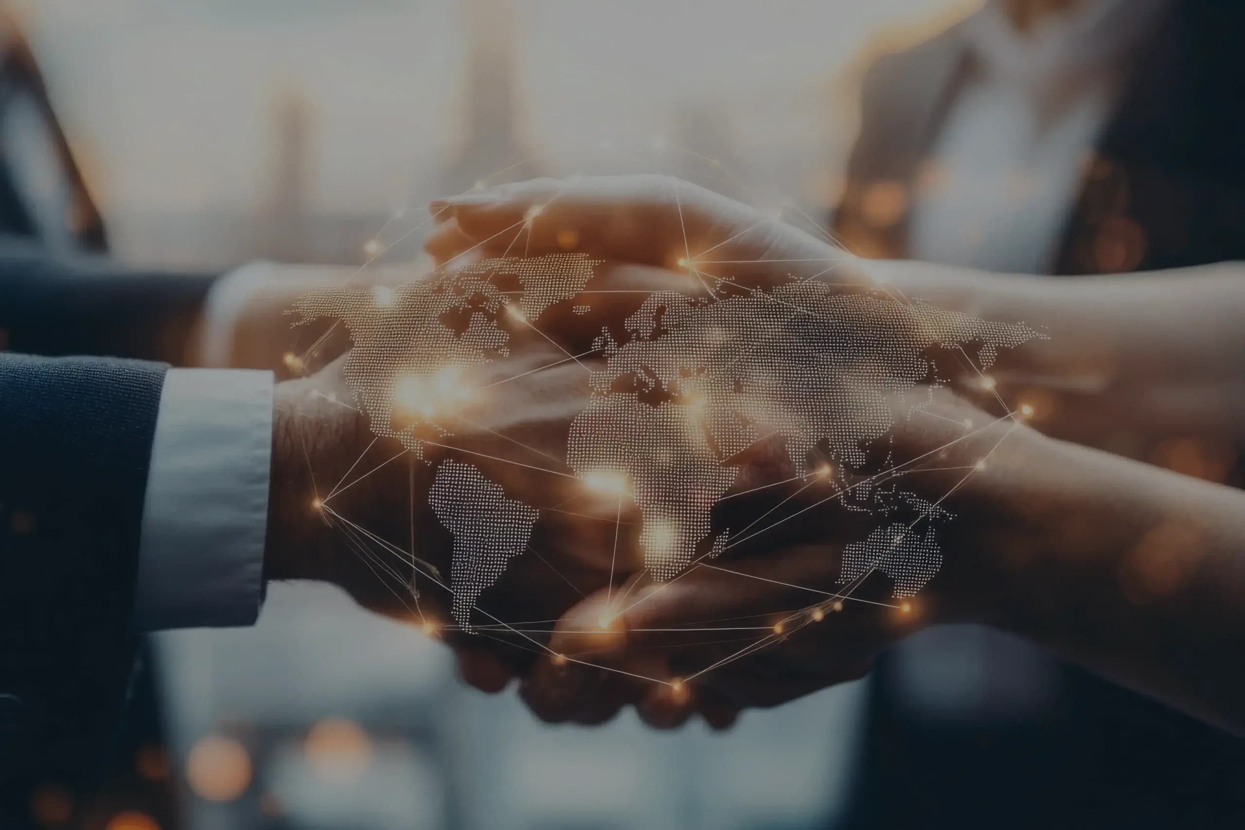 Two people shaking hands over an illuminated map of the world