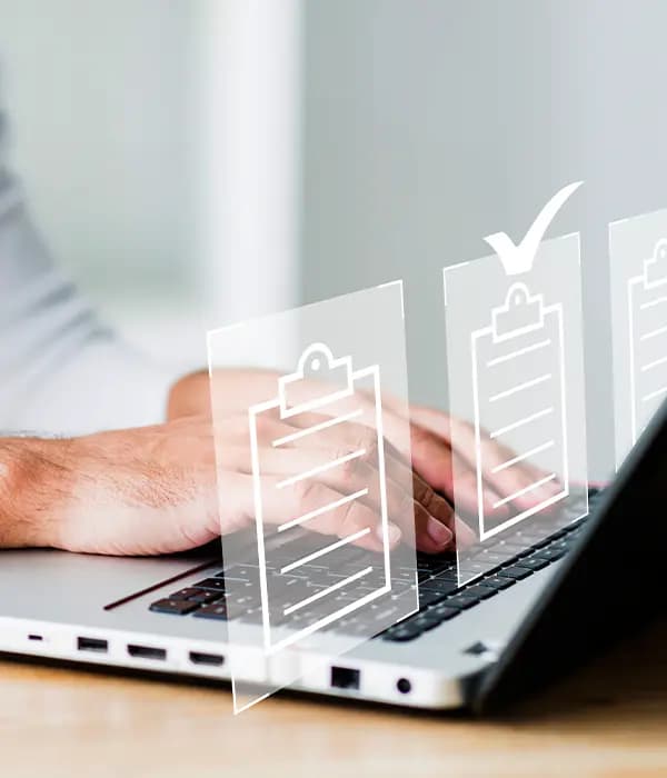Hands typing on a laptop with document approval icons floating above the keyboard