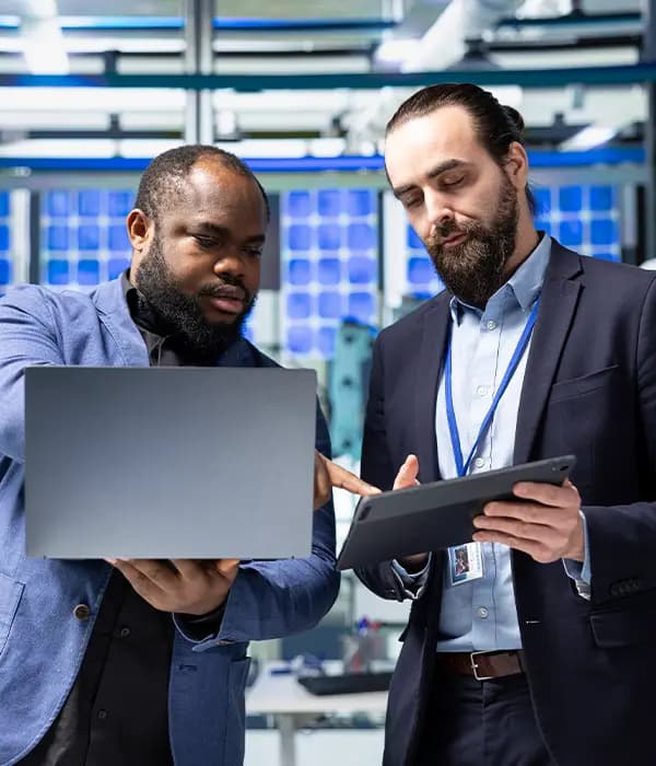 Two colleagues reviewing a system together on a laptop in a server room